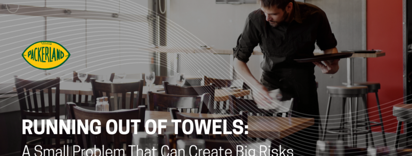 Packerland's blog header image contains the Heading of the blog, Running Out of Towels; a Small Problem That Can Create Big Risks. Behind the title, a restaurant employee is using a towel from a commercial towel service to wipe down empty tables